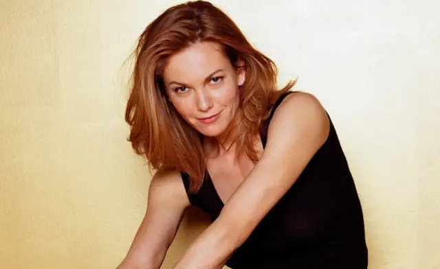 Diane Lane, znana z wielu filmów, w czarnej bluzce na tle żółtej ściany.