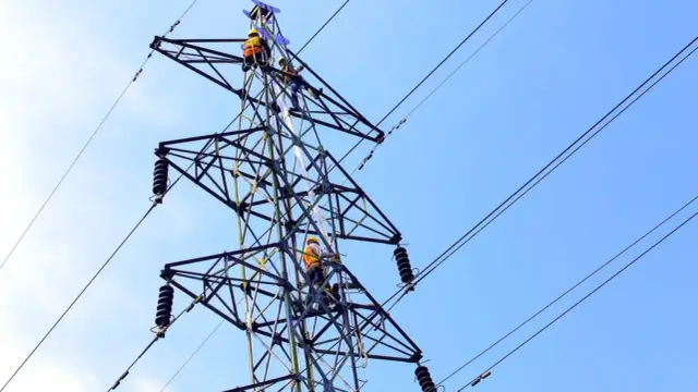 Pracownicy na słupie energetycznym. Zastanawiasz się, ile można dostać za słup na działce? To nie jest zwykły słup, to część infrastruktury energetycznej!