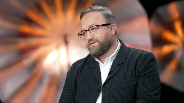 Bartłomiej Kasprzykowski w okularach i marynarce, opowiadający o swoich filmach.