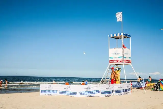 Ratownik na plaży czeka na sygnał. Biała flaga co oznacza? Bezpieczeństwo i spokój, idealne warunki do kąpieli.