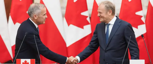 Uśmiechnięci politycy ściskają sobie dłonie na tle flag Kanady. To symboliczne spotkanie, które umacnia więzi między Polską a Kanadą.
