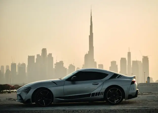 Srebrne sportowe auto na tle panoramy Dubaju. Idealne do wynajem samochodu Dubaj.