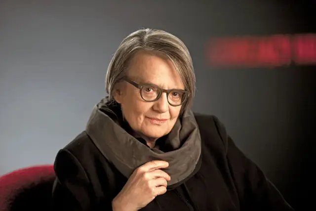 Portret Agnieszki Holland, reżyserki znanej z poruszających filmów, w okularach i z szalikiem.