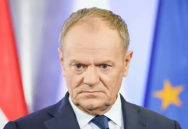 Donald Tusk zamyślony, w tle flagi Polski i UE. Czy najnowszy sondaż wyborczy CBOS przyniesie mu sukces?
