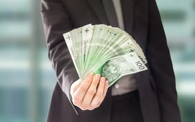 Dłoń w garniturze trzyma wachlarz banknotów 100 zł. To może być podsumowanie dzisiejszych stalexport notowań.