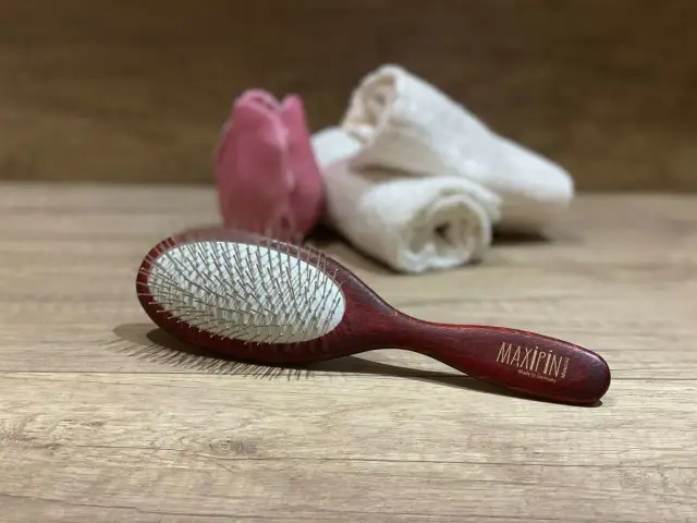 Elegancka szczotka dla maltańczyka z drewnianą rączką, idealna do pielęgnacji jego białej sierści.