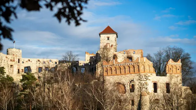 Ruiny zamku na wzgórzu, jeden z największych zamków w Polsce, z wieżą i ceglanymi arkadami.