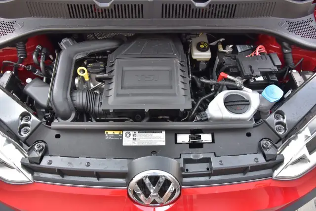 Silnik 1.0 TSI w czerwonym samochodzie, widok z góry. Widać turbosprężarkę, akumulator i płyny.