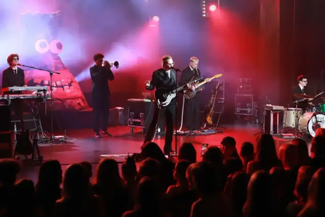 Bracia Kacperczyk na scenie, w otoczeniu instrumentów i świateł, grają dla publiczności.