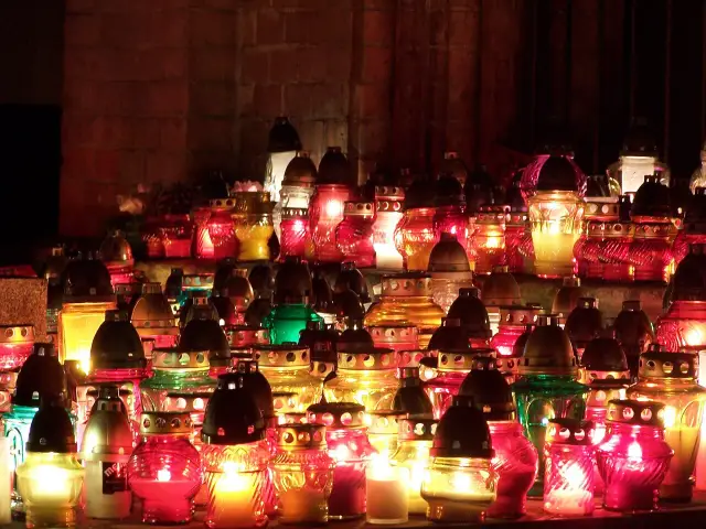 Płonące znicze, symbol modlitwy za zmarłych rodziców, tworzą ciepłe światło wśród ceglanych murów.
