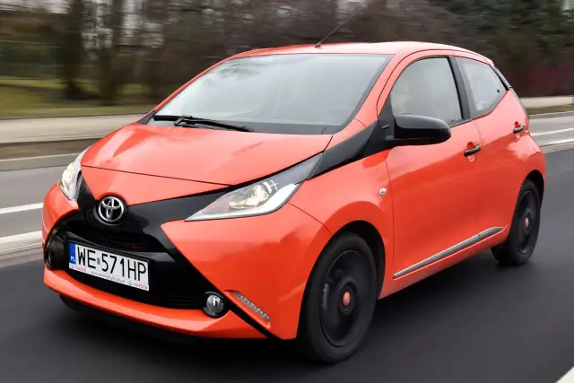 Pomarańczowa Toyota Aygo w ruchu. Zastanawiasz się, ile pali Toyota Aygo? Ten miejski samochód jest znany z niskiego spalania.