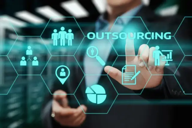 Biznesmen dotyka ekranu z ikonami symbolizującymi outsourcing: zespół, analizę, lokalizację, dokumenty i prezentację.