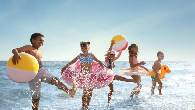 Dzieci bawią się na plaży z dmuchanymi zabawkami, idealny hotel z animacjami dla dzieci.