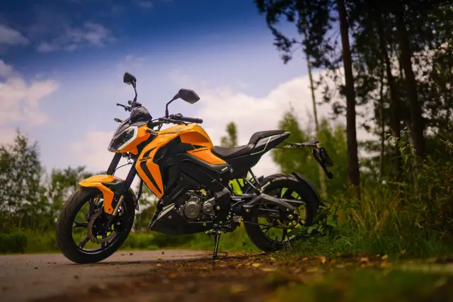 Pomarańczowy motocykl Keeway RKF 125 na tle lasu. Sprawdź keeway rkf 125 dane techniczne i poczuj wolność.