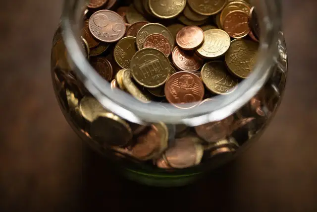Skarbonka pełna monet euro, symbolizująca odprawę dla nauczyciela przechodzącego na świadczenie kompensacyjne.