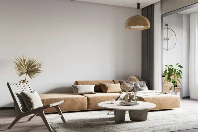 Salon w stylu wabi sabi z beżową kanapą, plecionym fotelem i suszonymi trawami. Naturalne materiały i stonowana paleta barw tworzą spokojną atmosferę.