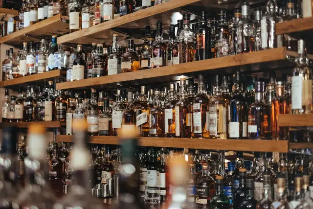 Półki pełne butelek whisky. Zastanawiasz się, ile kalorii ma whisky z colą? To zależy od ilości i rodzaju alkoholu.