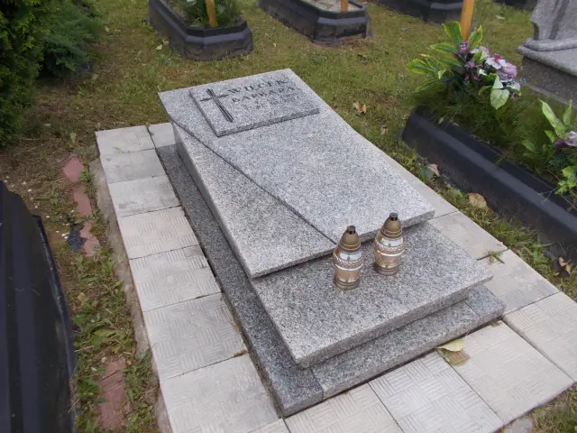 Nagrobek z granitu z imionami i datami, ozdobiony krzyżem i dwoma zniczami. Grobonet Jastrzębie Zdrój.