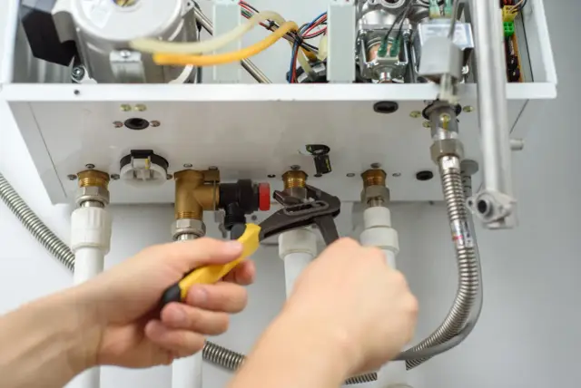 Serwisant dokręca kluczem instalację gazową w mieszkaniu, zgodnie z przepisami.