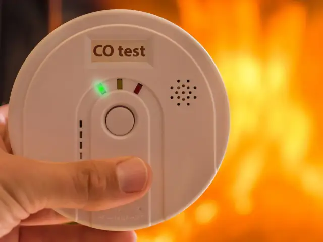 Dłoń trzyma czujnik czadu z napisem "CO test" i zieloną diodą. Sprawdź, jak przetestować czujnik czadu, by zapewnić bezpieczeństwo.
