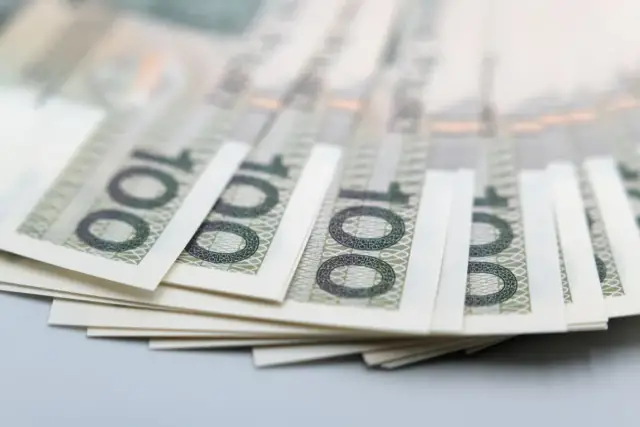 Stos banknotów 100 zł, symbolizujący pfron dofinansowanie do samochodu.