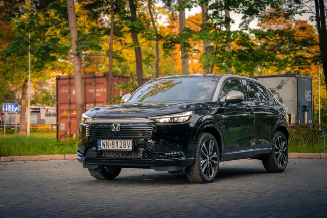 Czarny Honda HR-V na tle jesiennych drzew i kontenerów. Elegancki SUV gotowy na przygodę.
