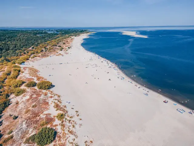 Piękna plaża z turkusowym morzem i zielonym lasem. Idealne miejsce, gdzie nad morze we wrześniu, by cieszyć się słońcem i spokojem.