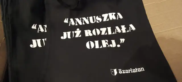Czarna torba z napisem "ANNUSZKA JUŻ ROZLAŁA OLEJ." i logo Szarlatan.