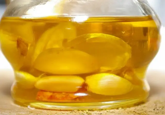 Słoik z oliwą i ząbkami czosnku, idealny do przygotowania aromatyzowanej oliwy czosnkowej i ziołowej bez ryzyka botulizmu.