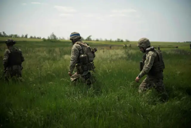 Żołnierze w kamuflażu ostrożnie przemieszczają się przez wysokie trawy. Czy to przygotowanie do zasadzki, czy patrol?