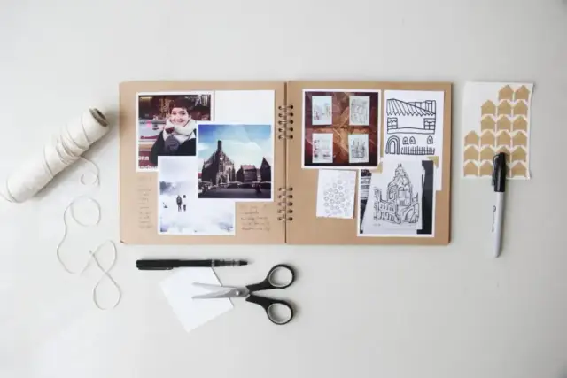 Otwarty album na zdjęcia, zdjęcia, rysunki, nożyczki i sznurek. To jest scrapbooking co to jest – tworzenie własnych, unikalnych pamiątek.