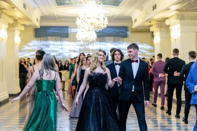 Młoda para idzie na bal. Czy w szkole zaocznej jest studniówka? Eleganckie stroje, błyszczące suknie i garnitury świadczą o wyjątkowej okazji.