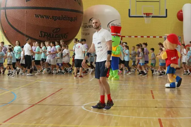 Trener z mikrofonem i dzieci w hali sportowej. Czy uda się znaleźć wszystkich uczestników?