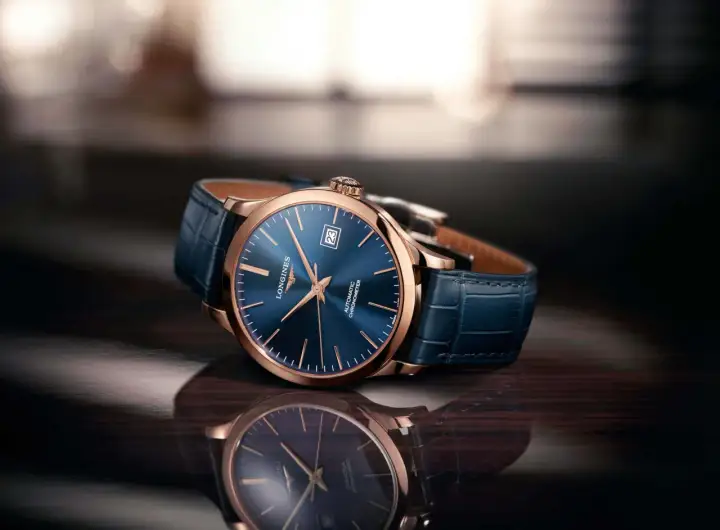 Elegancki zegarek damski rose gold z granatową tarczą i skórzanym paskiem, odbijający się w błyszczącej powierzchni.