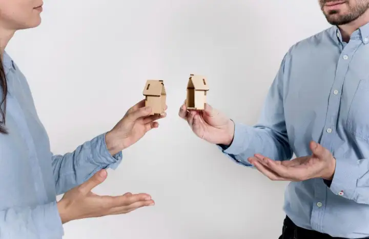 Rozdzielność majątkowa a wspólny dom: dwoje ludzi trzyma miniaturowe domki, symbolizujące podział majątku.
