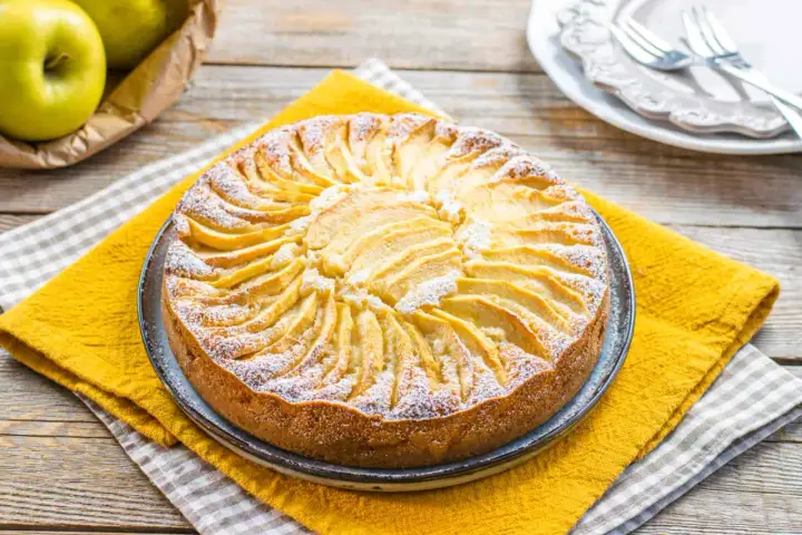Torta di mele decorata con fettine disposte a raggiera, spolverata di zucchero a velo. Un'idea per torte senza zucchero.