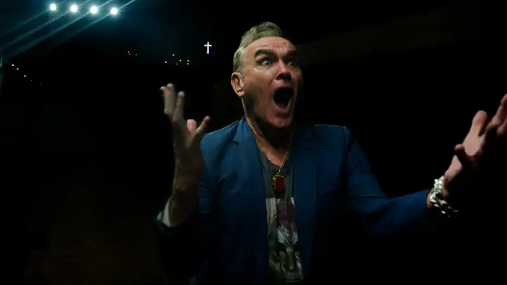 Morrissey en Zaragoza, con gesto dramático y las manos alzadas, bajo luces y una cruz.