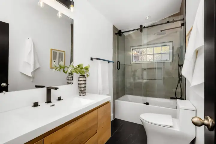 Modernos baños pequeños con lavabo de madera, ducha con mampara de cristal y azulejos grises.