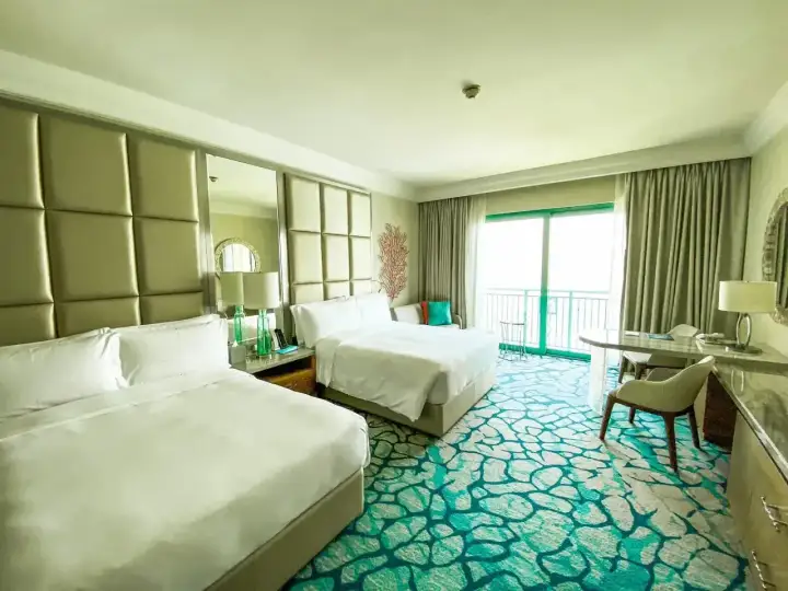 Pokój hotelowy z dwoma łóżkami i dywanem w kolorze mokrej wody.