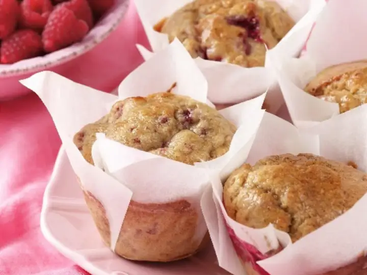 Leckere protein muffins rezept mit Himbeeren, frisch gebacken und auf einem rosa Teller angerichtet.