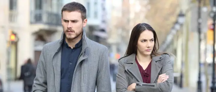 Een man en vrouw lopen met een boze blik uit elkaar. Ze lijken conflict zoekende mensen, elk met hun eigen gedachten.
