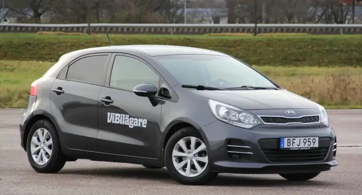 Mörkgrå Kia Rio med texten "ViBilägare" på sidan. En bil som kan ha ett kia rio problem.