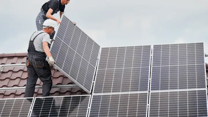 Instaladores colocan placas solares en un tejado, asegurando el anclaje para la energía limpia.