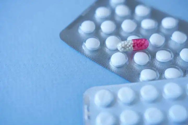 Dwie blistry z białymi tabletkami i jedna kapsułka z różowym i białym wypełnieniem. Zastanawiasz się, pulnozin na co?
