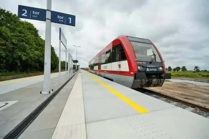 Czerwony pociąg Arriva czeka na peronie. Tablice wskazują tor 1 i tor 2, sugerując podróż między Toruniem a Lublinem.