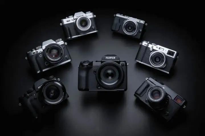 Kolekcja aparatów Fujifilm ułożona w okrąg. W centrum duży, czarny korpus, a wokół niego mniejsze modele, w tym X-T20. Każdy aparat to potencjalna pełna klatka możliwości.