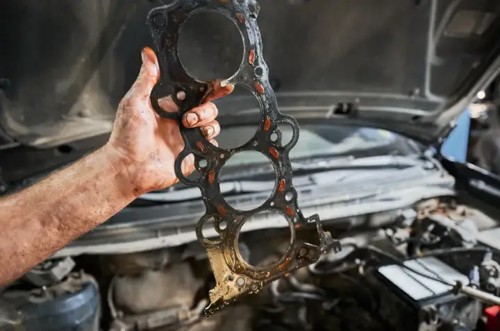 Uszczelka pod głowicą kosztuje sporo, a ta wygląda na zużytą. Mechanik pokazuje ją po demontażu silnika.