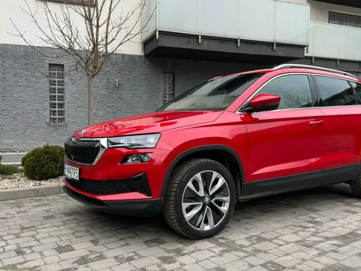 Czerwona Skoda Karoq na tle nowoczesnego budynku. Wiele osób szuka skoda karoq opinie, by podjąć decyzję o zakupie.
