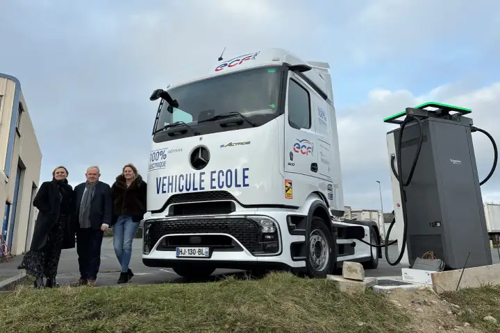 Trois personnes posent devant un camion école 100% électrique, prêt à être rechargé. L'avenir des camions électriques est en marche.
