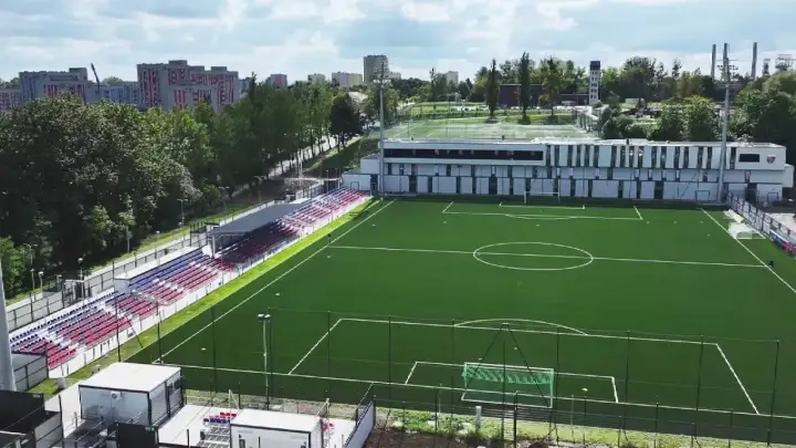 Nowy stadion Polonii Bytom z zieloną murawą, trybunami w kolorach czerwonym i niebieskim oraz nowoczesnym budynkiem klubowym.